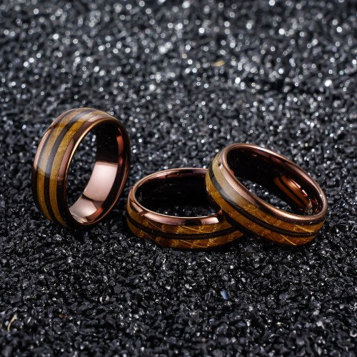 Three wooden and metal rings with striped wood grain patterns on a textured black surface, showcasing handcrafted eco-friendly design