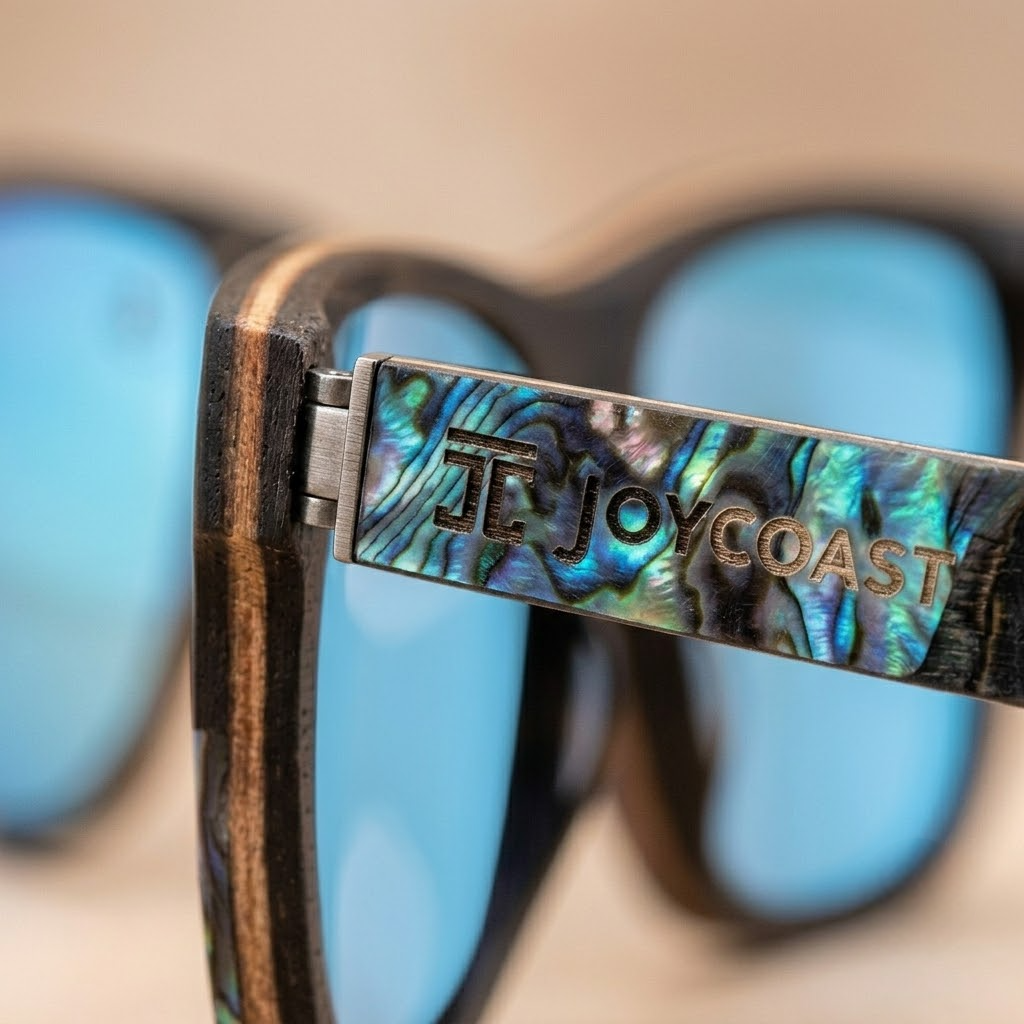 Close-up of abalone-pattern temple on sunglasses with 'Tj Joycoast' text and hinge
