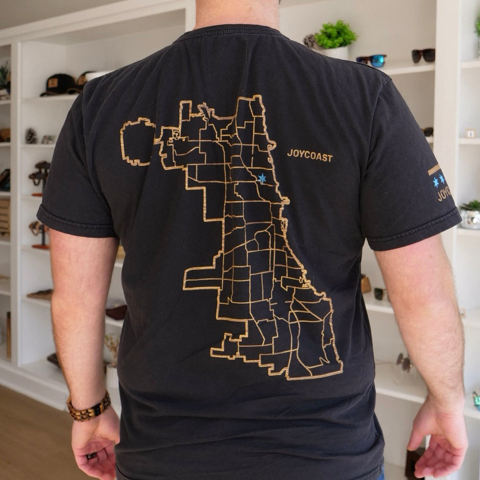 Person wearing a black t-shirt with a map of chicago design on the back, standing in the joycoast retail store in chicago