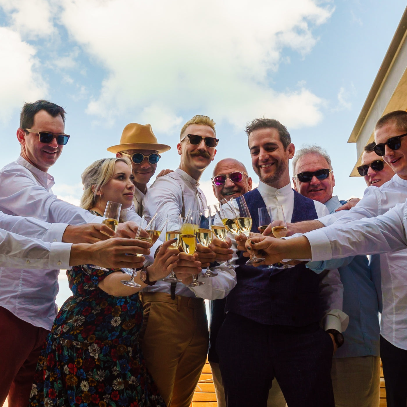 A diverse group of men and women cheerfully holding glasses of wine, celebrating together in a social setting.