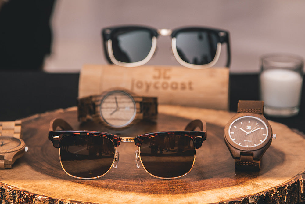 A wooden watch and sunglasses displayed on a wooden stand, showcasing a stylish accessory arrangement.
