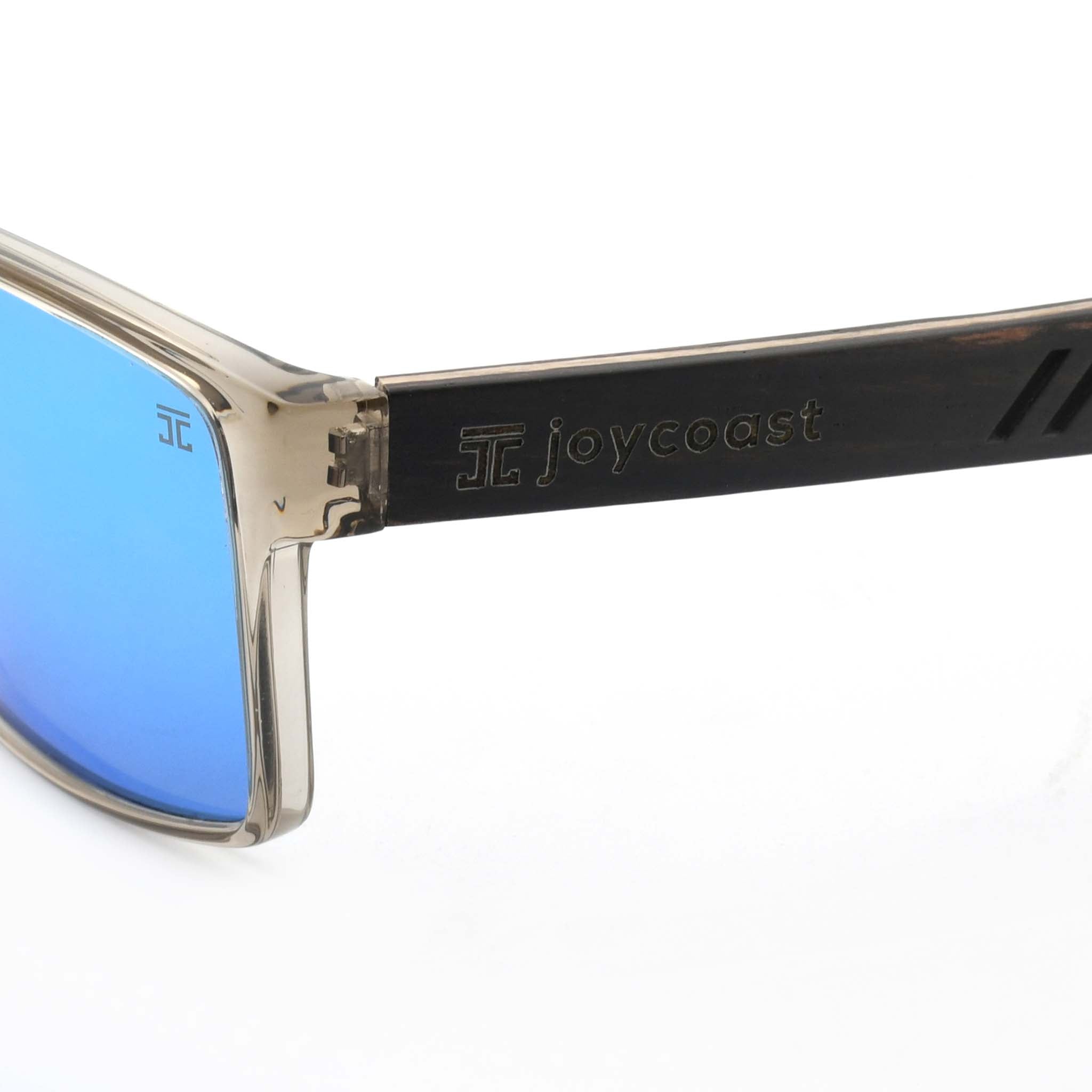 Close-up of a wooden sunglasses arm with the "Joycoast" logo and slogan "It's gonna be a good day." engraved.