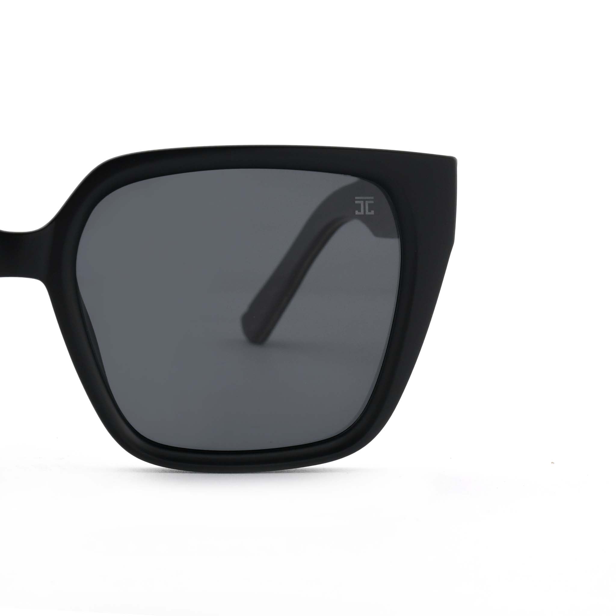 Partial view of Joycoast black wooden sunglasses showing the dark lens and wooden frame on a white background.