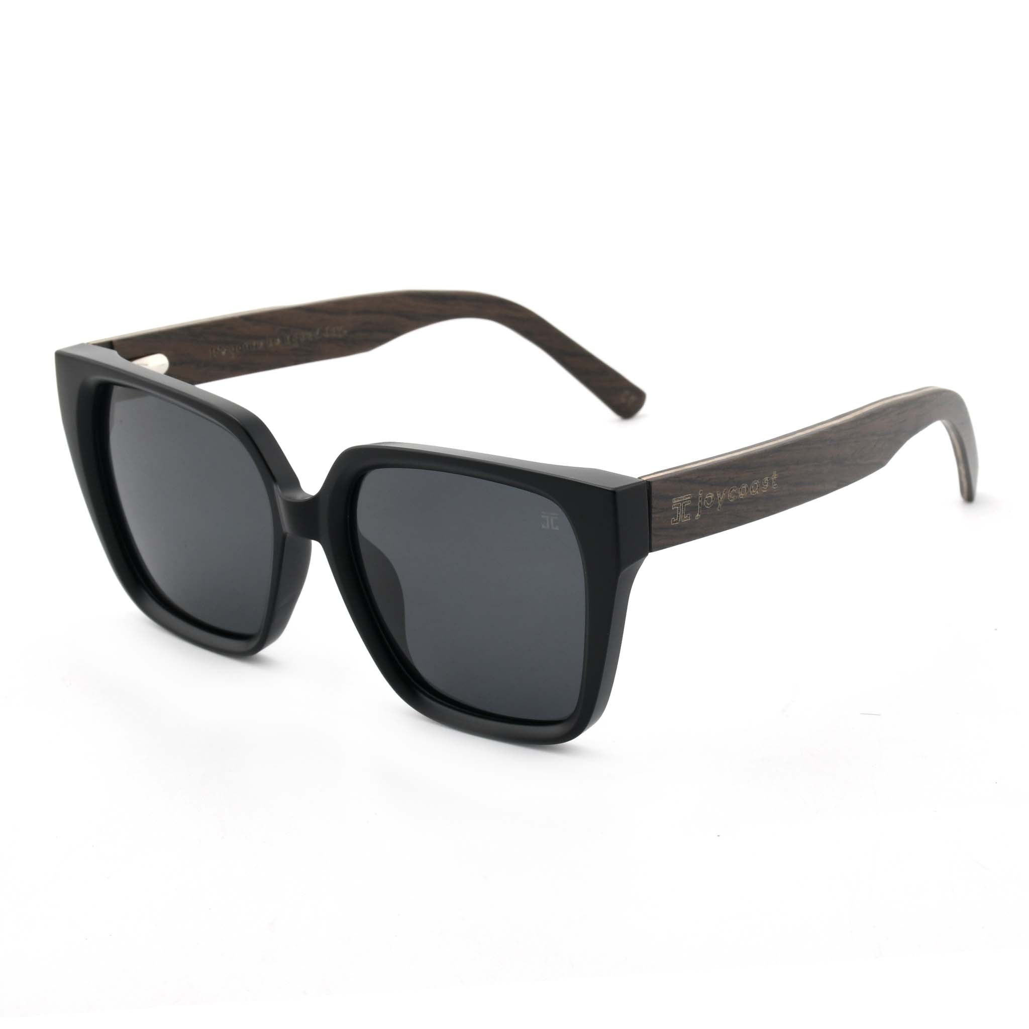 Joycoast black sunglasses with dark lenses and wooden arms, viewed from a side angle on a white background.
