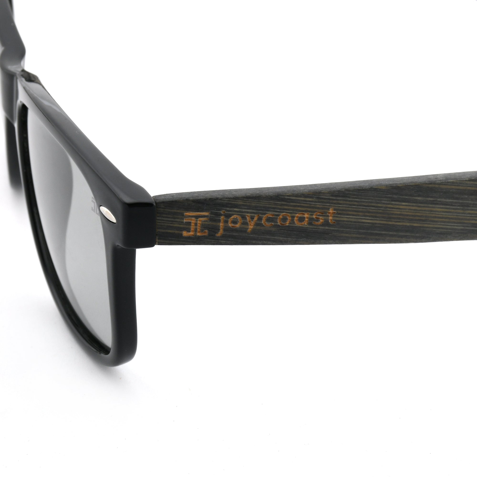 Close-up of a black wooden eyeglasses arm with the "Joycoast" logo engraved.