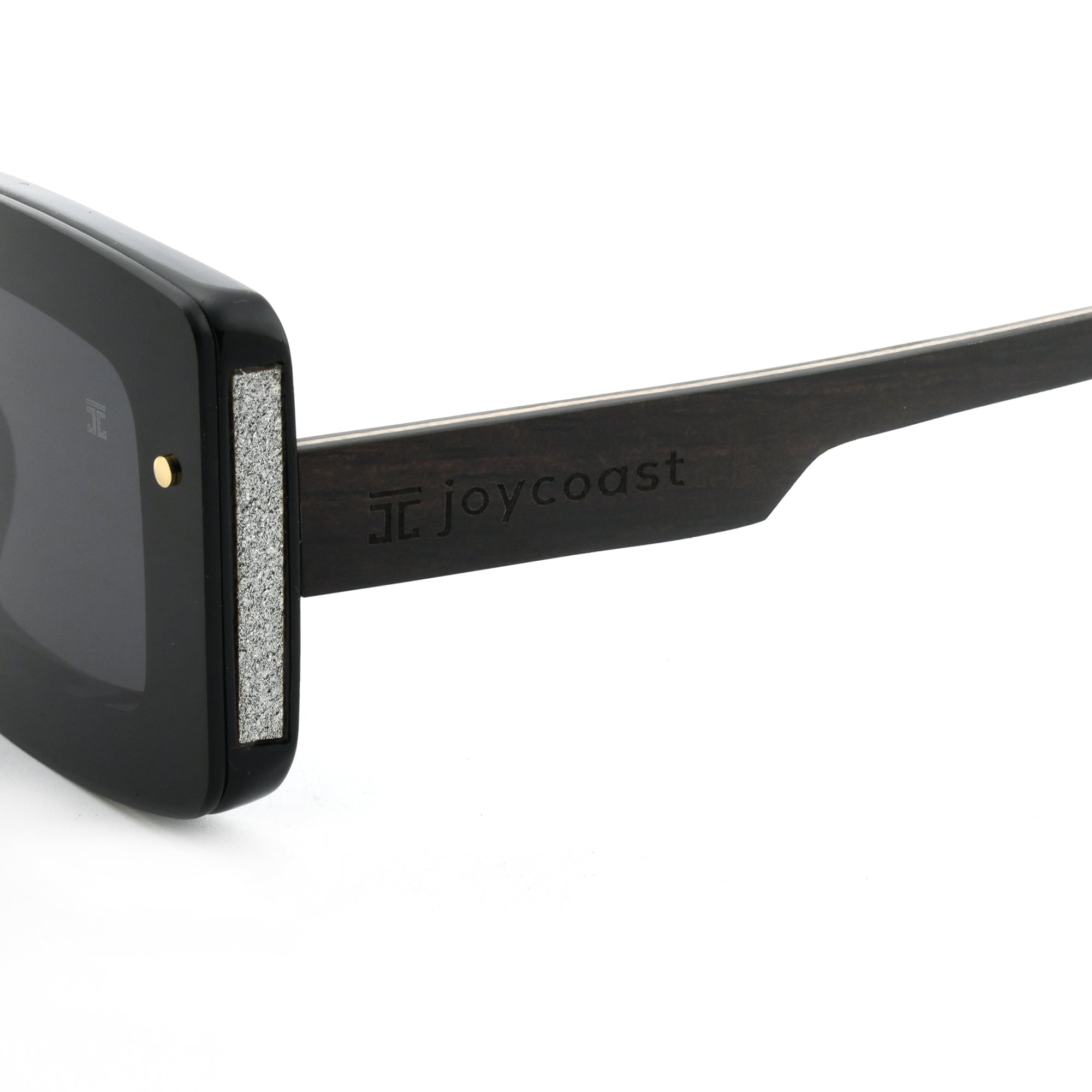 Close-up of a black wooden sunglasses arm with the "Joycoast" logo engraved.