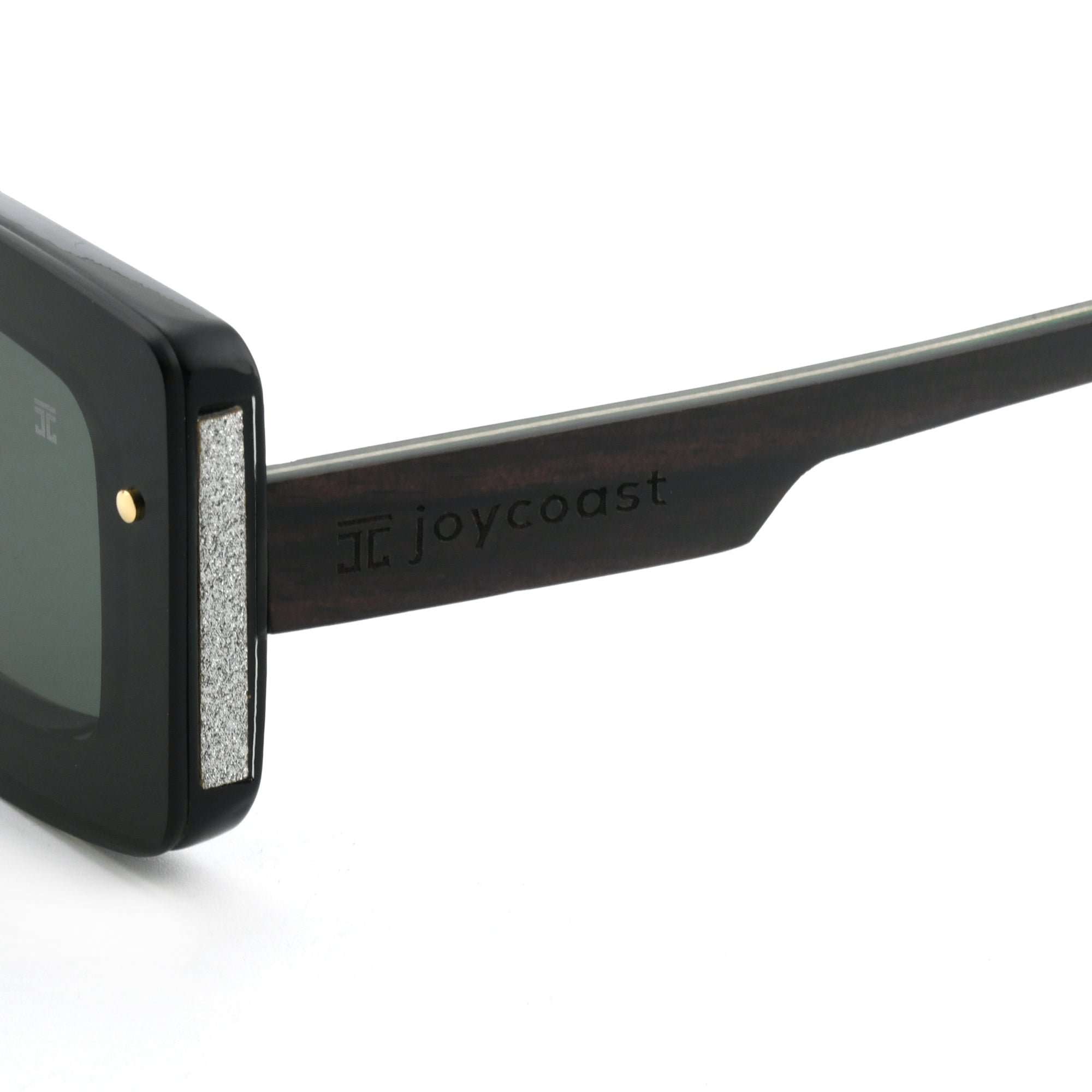 Close-up of a black wooden sunglasses arm with the "Joycoast" logo engraved.