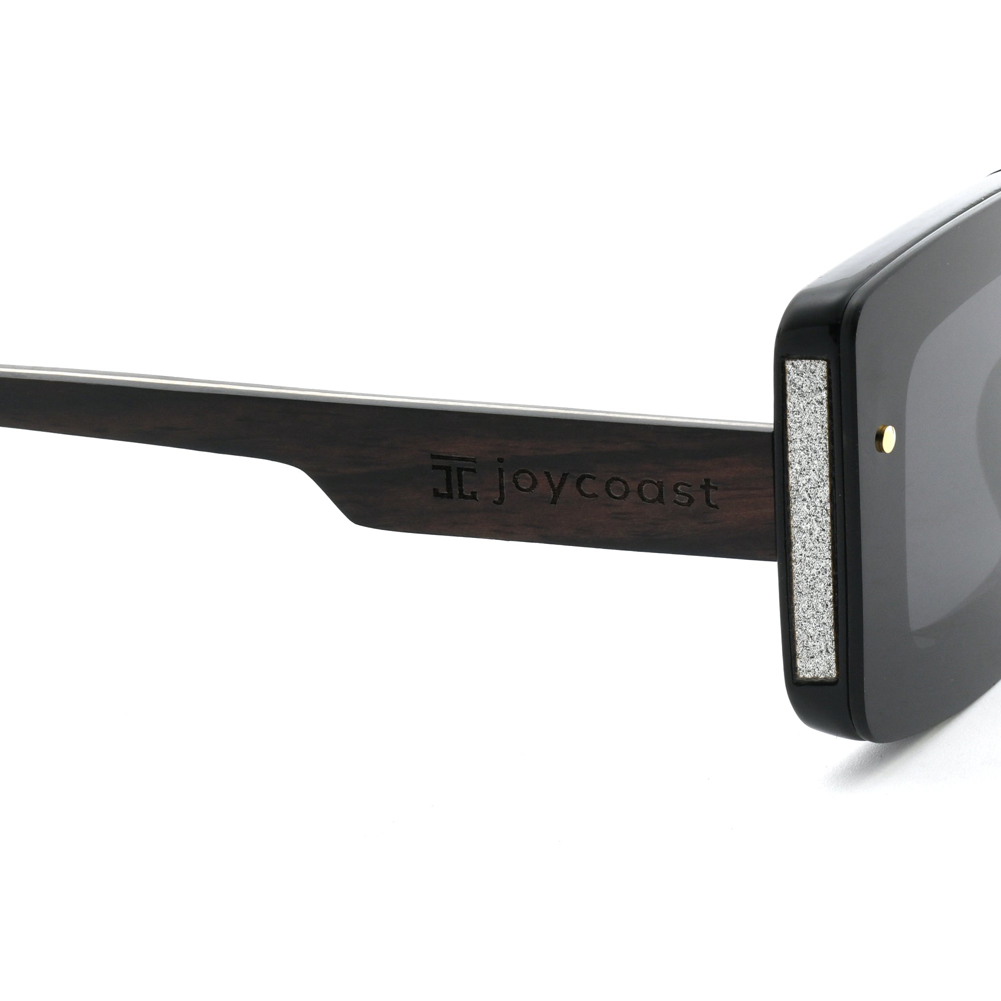 Close-up of a black wooden sunglasses arm with the "Joycoast" logo engraved near the hinge.