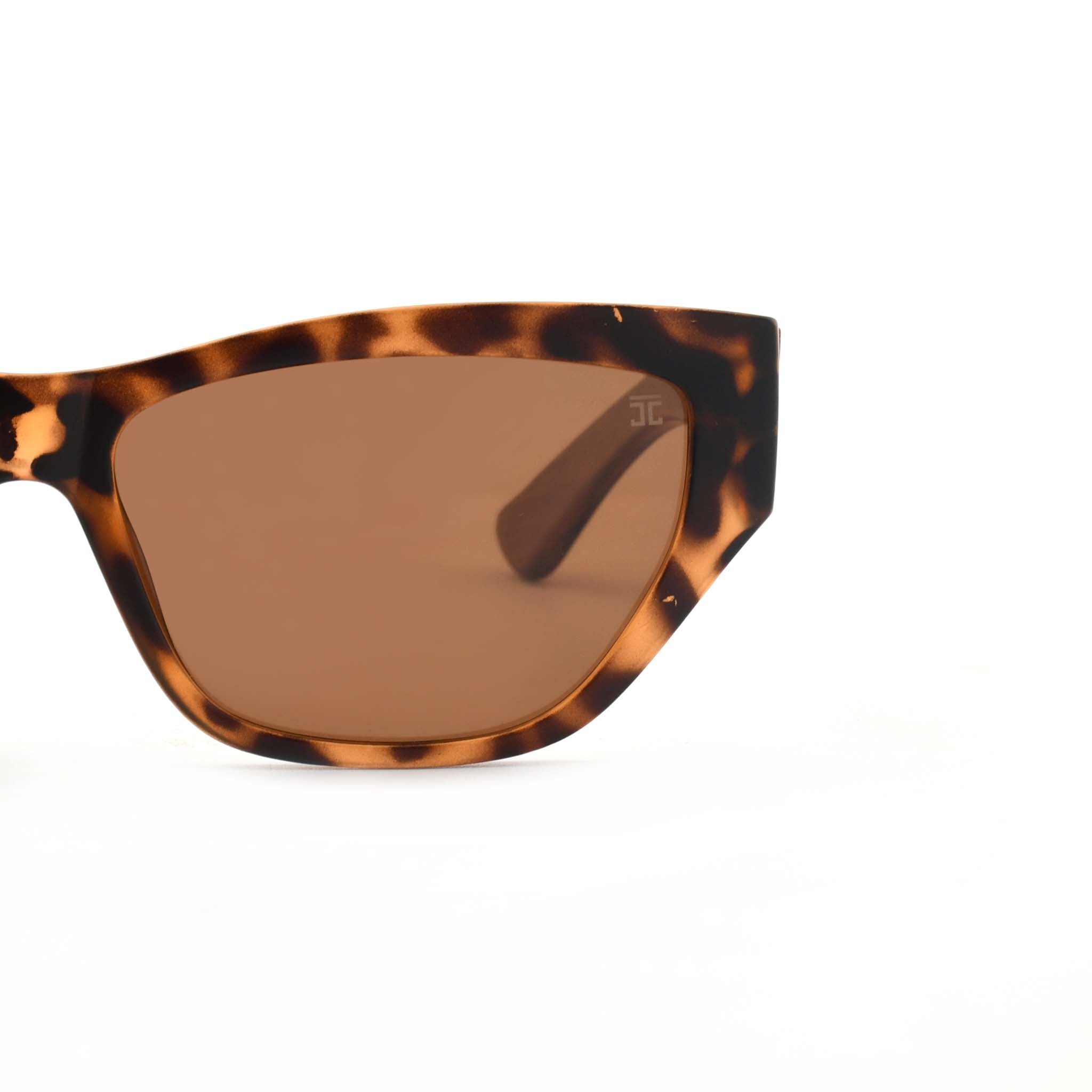 Partial view of Joycoast Juniper tortoise shell sunglasses showing the brown lens and wooden arm on a white background.