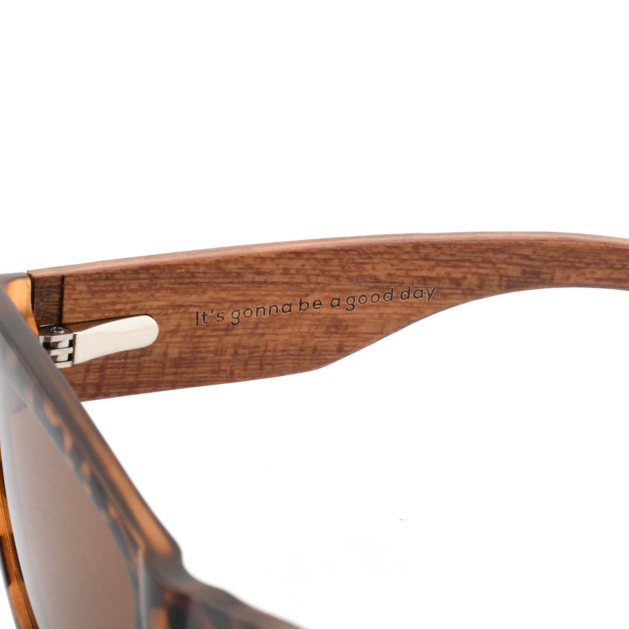 Close-up of a wooden sunglasses arm with the engraved slogan "It's gonna be a good day."