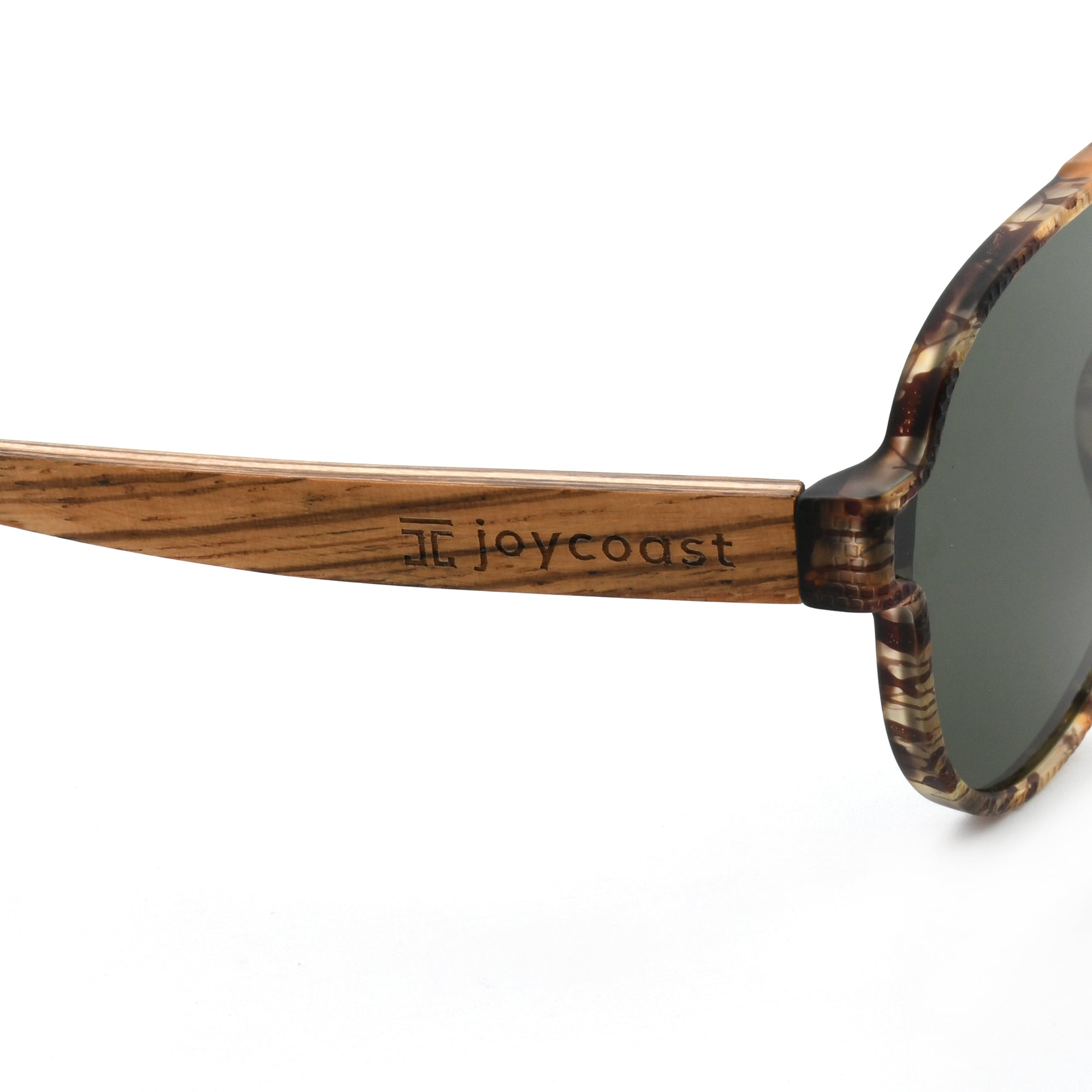 Close-up of Joycoast tortoise shell wooden sunglasses arm with "Joycoast" logo engraved near the dark green lens.
