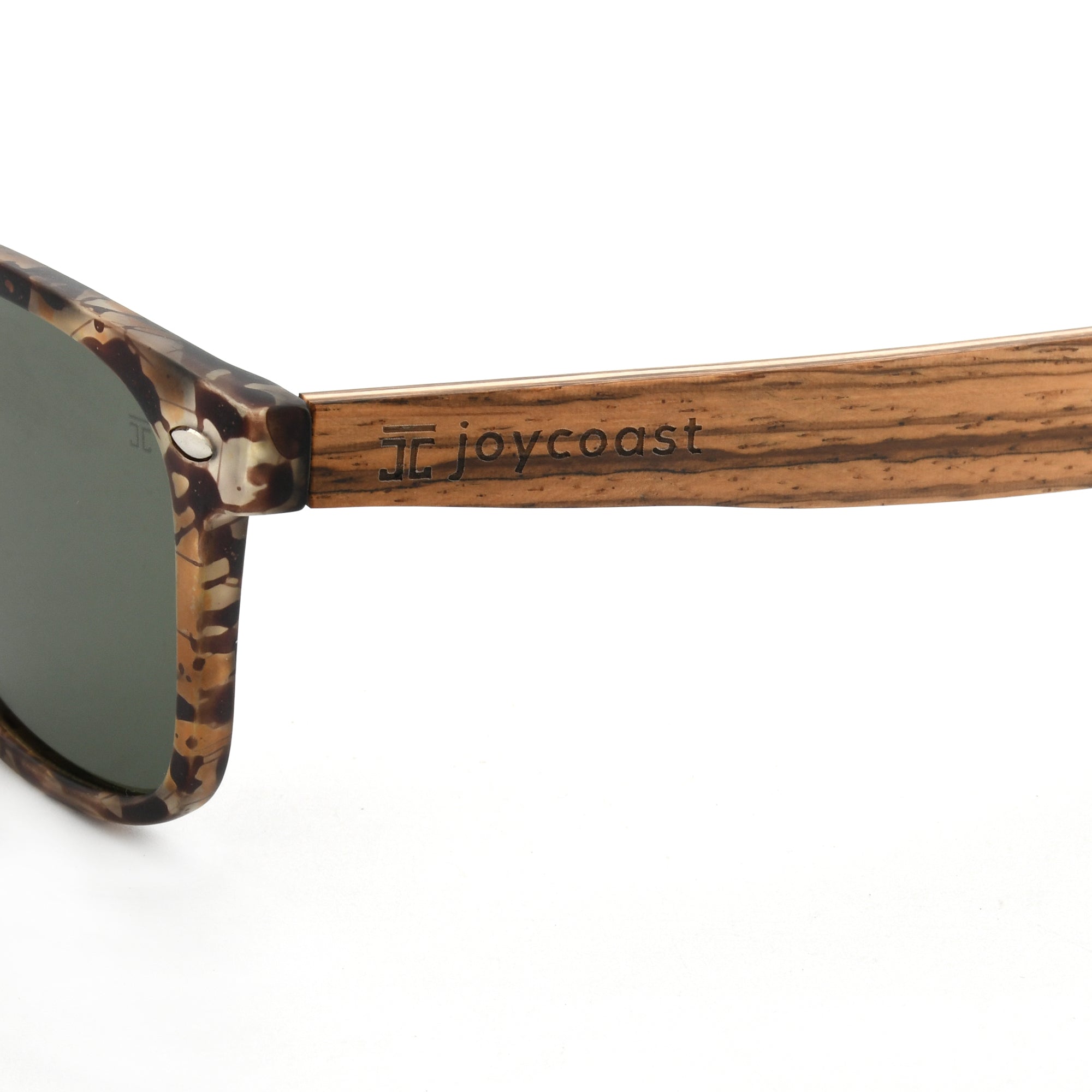 Close-up of a wooden sunglasses arm with the "Joycoast" logo engraved near the hinge.