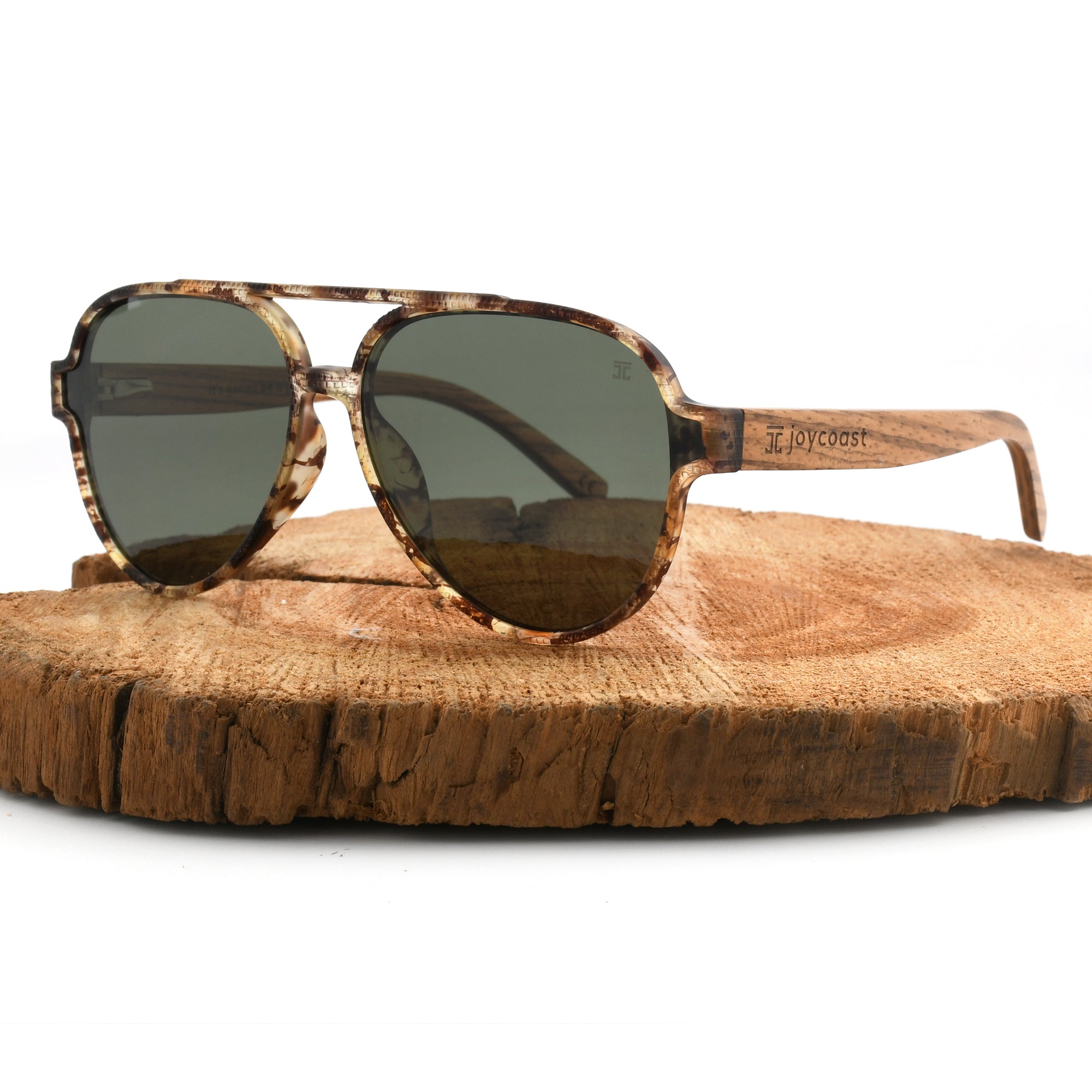 Joycoast tortoise shell wooden sunglasses with dark green lenses and a full wooden frame, displayed on a natural wood slice