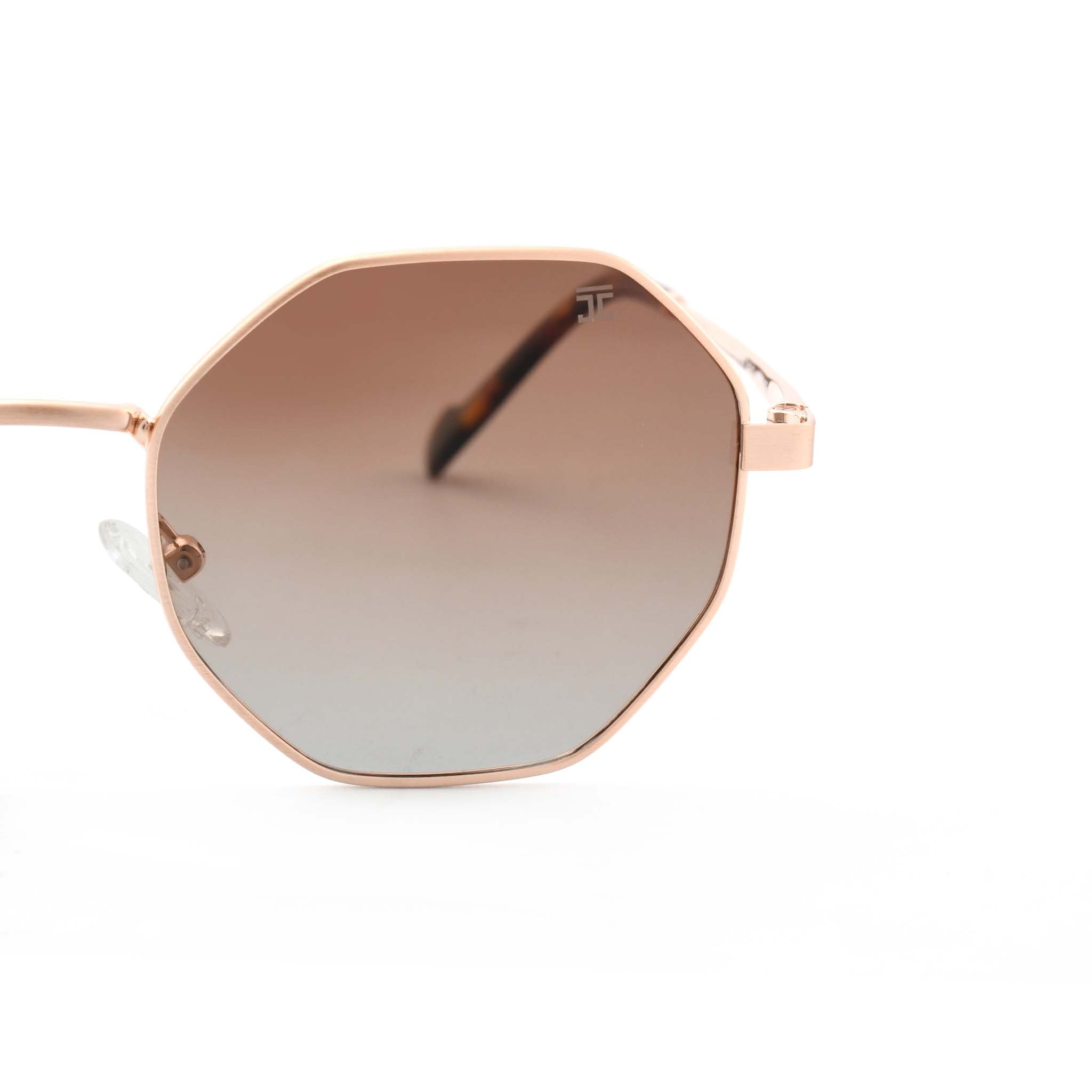Joycoast Vesuvio rose gold hexagon-frame sunglasses with red/brown gradient lenses, viewed from a side angle on a white background.
