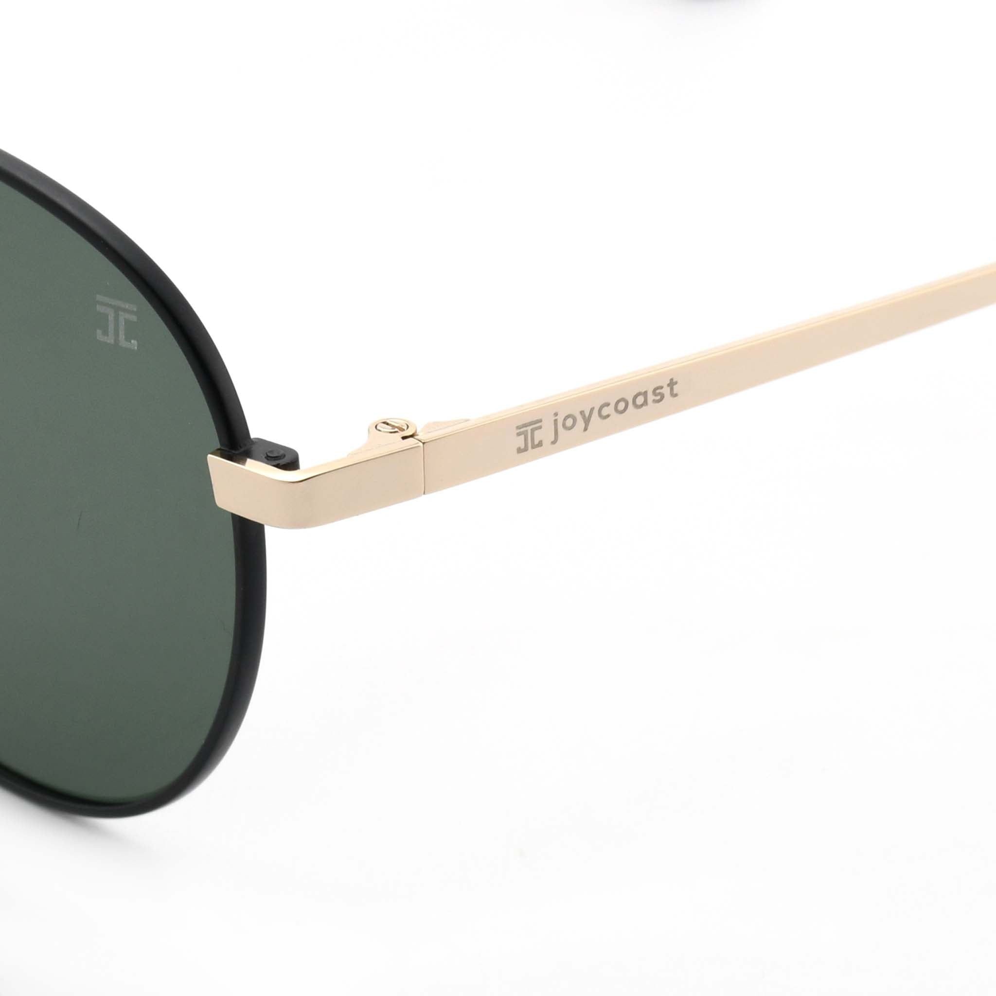 Close-up of the gold arm of Joycoast Willow sunglasses with "Joycoast" engraved near the dark green lens.