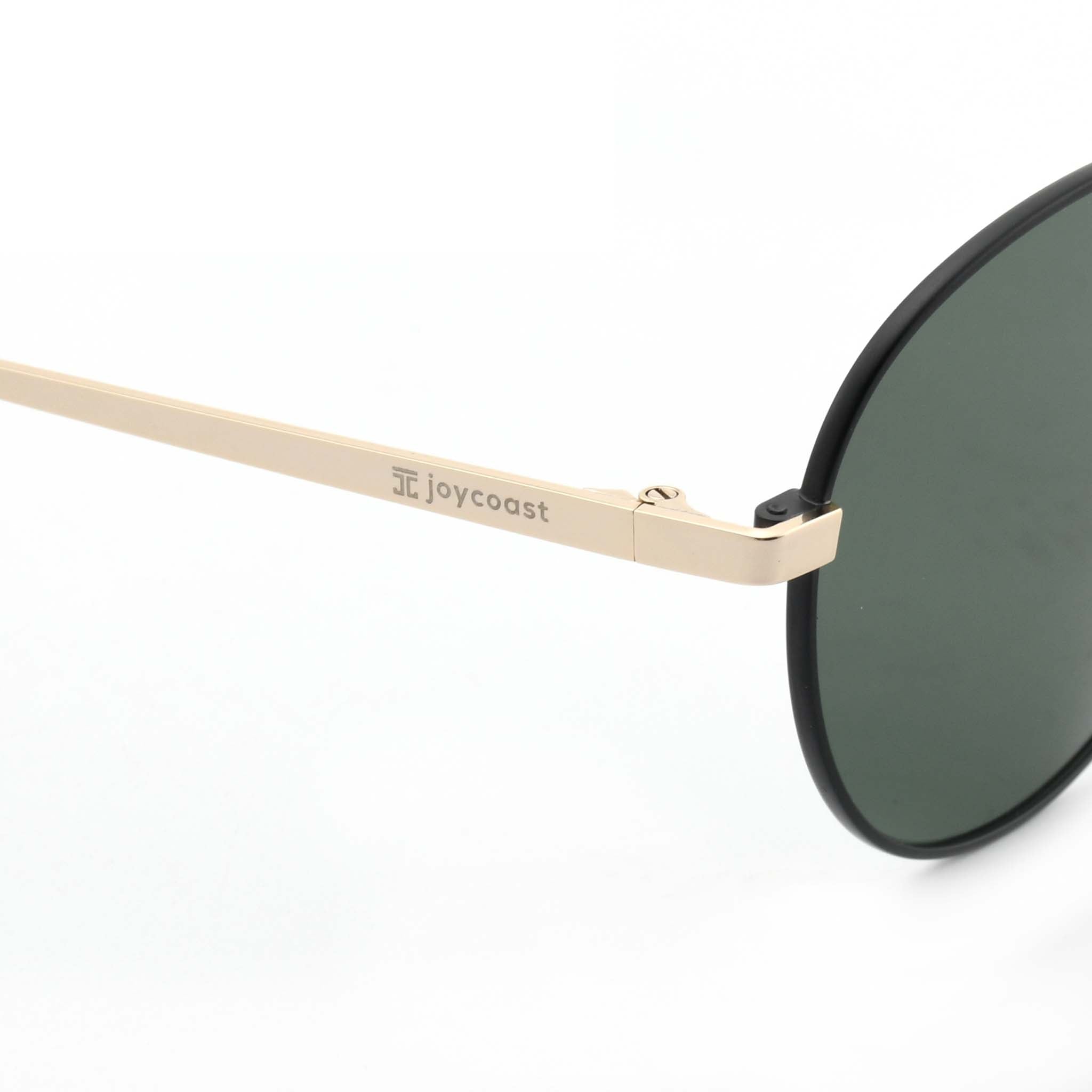 Close-up of the gold arm of Joycoast Willow sunglasses with "Joycoast" engraved near the dark green lens.
