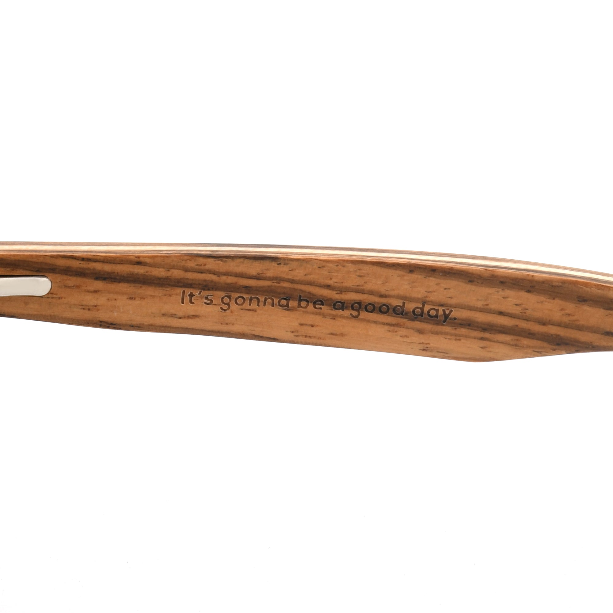 Close-up of a brown wooden sunglasses arm with the Joycoast slogan, "It's gonna be a good day." engraved.