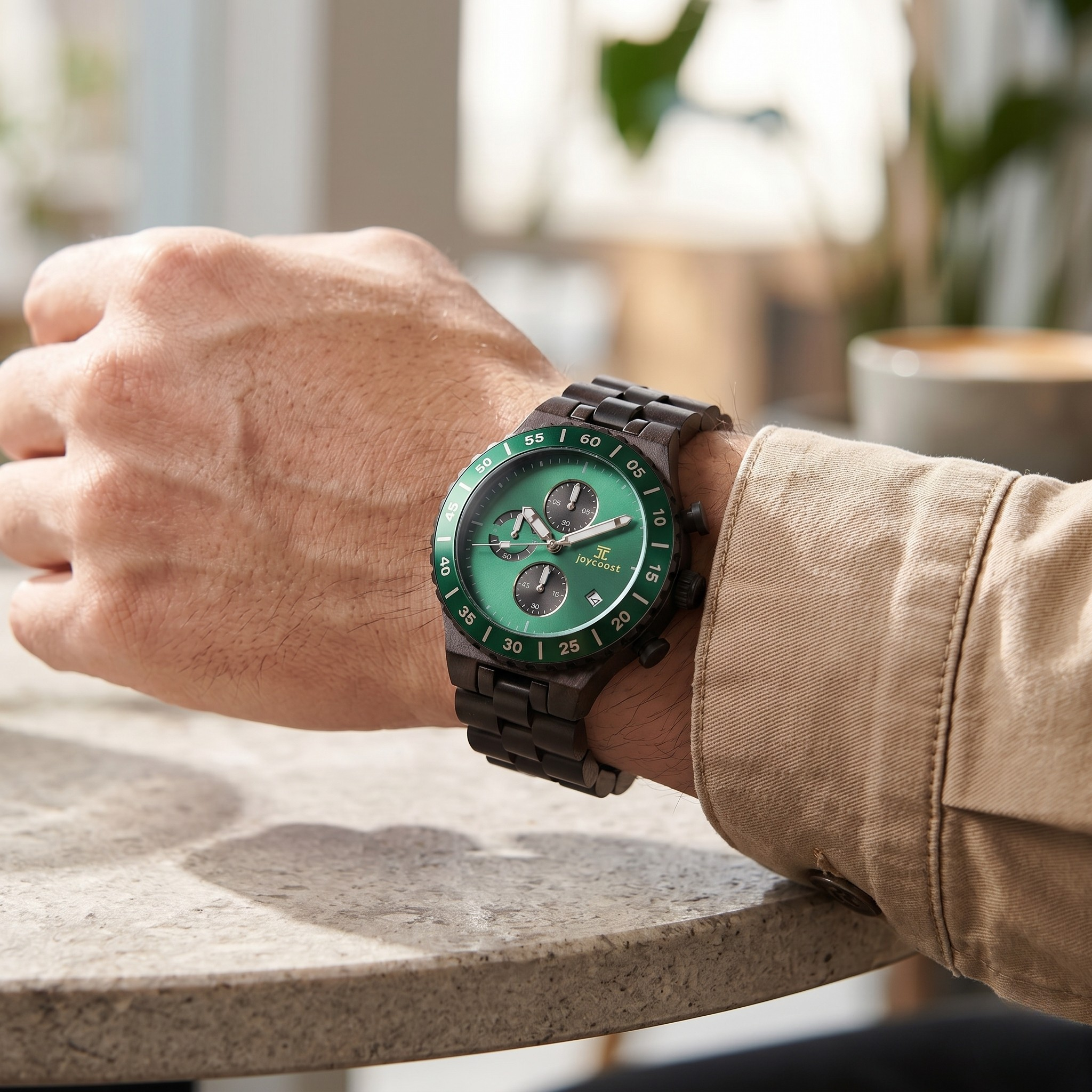 Lifestyle photo of a person wearing a Joycoast dark wooden chronograph watch featuring a vibrant emerald green dial and matching numbered bezel.