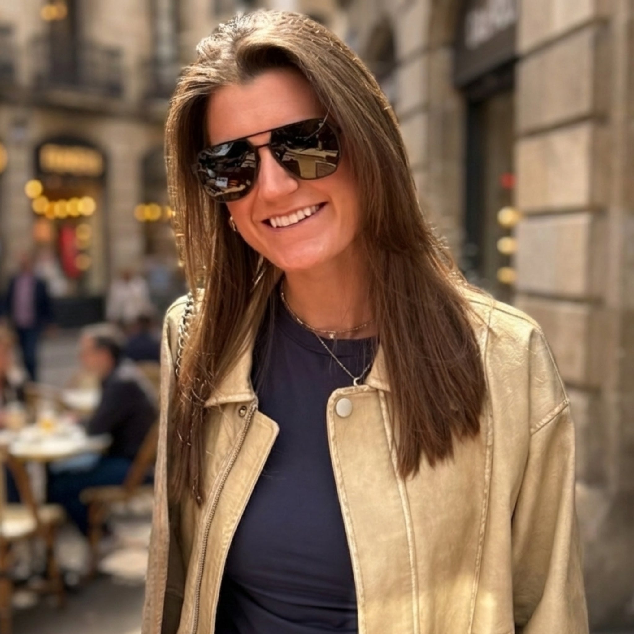 Wooden hexagon sunglasses with dark lenses and tan frame, worn by a smiling woman