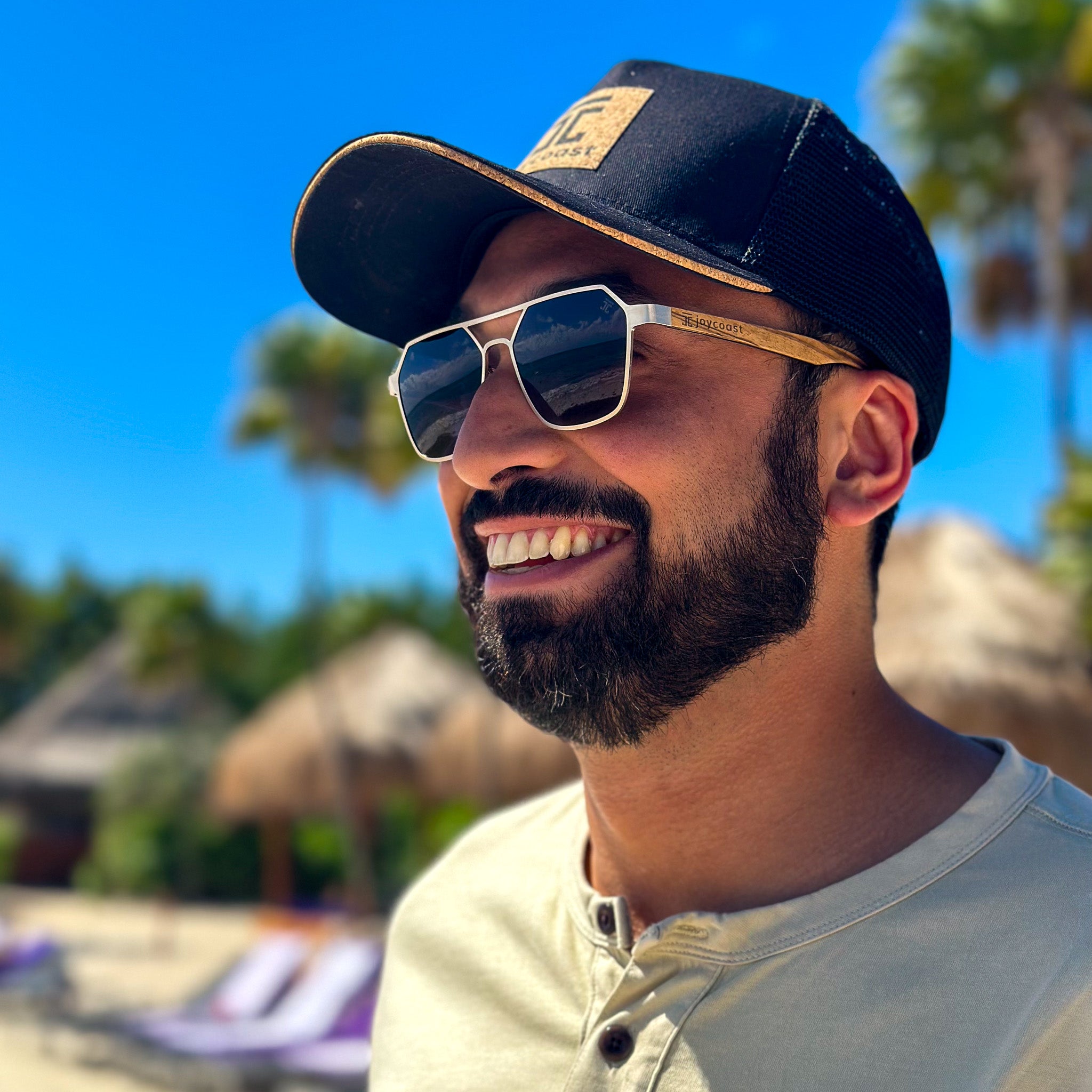 Wooden hexagon sunglasses with dark lenses and light tan frame, worn by a man outdoors