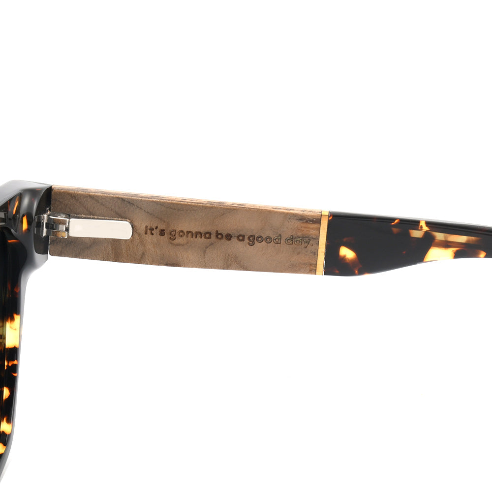 Wooden temple arm with metal hinge and engraved text on tortoiseshell sunglasses