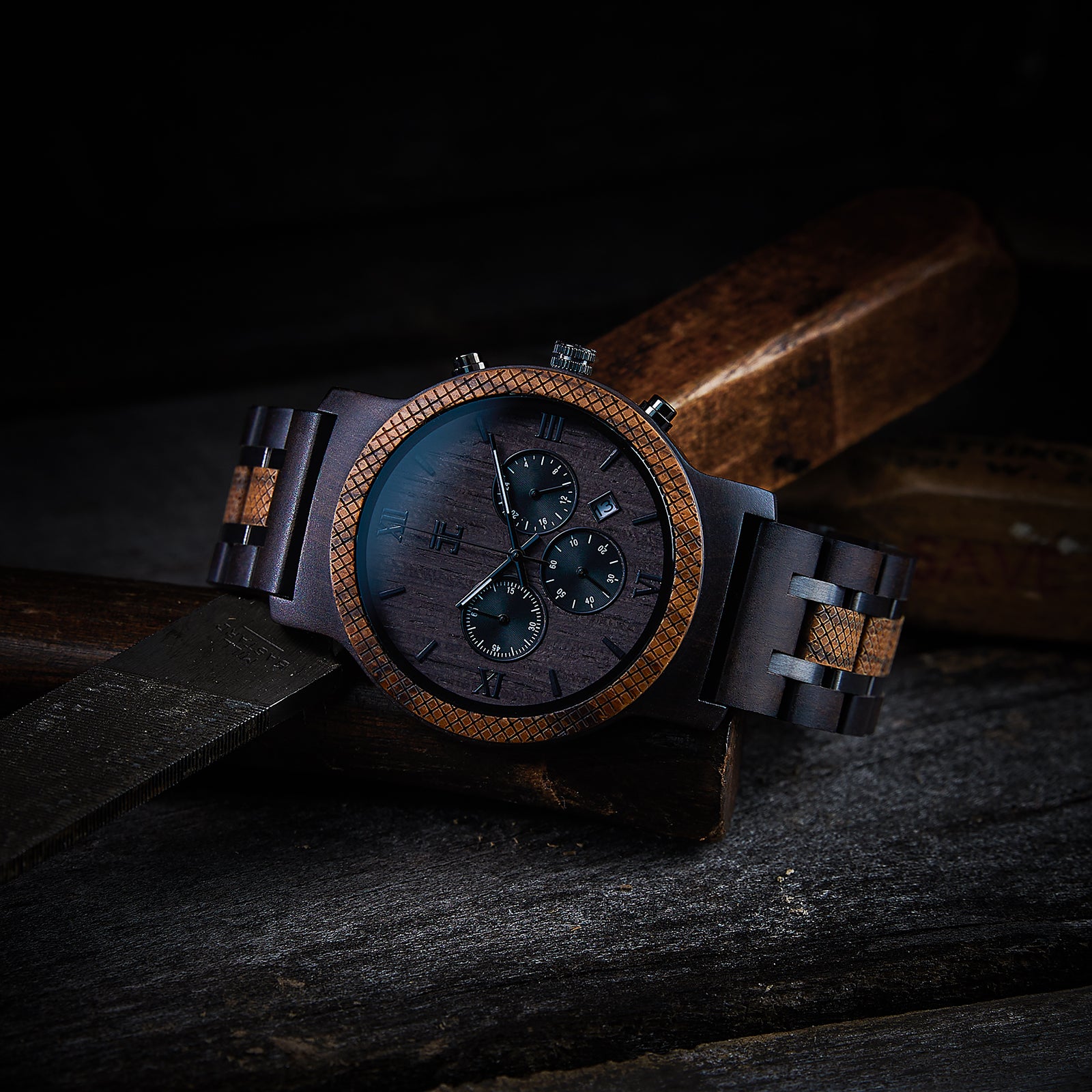 Handcrafted wooden men's watch with dark wood dial and patterned bezel on rustic wood surface