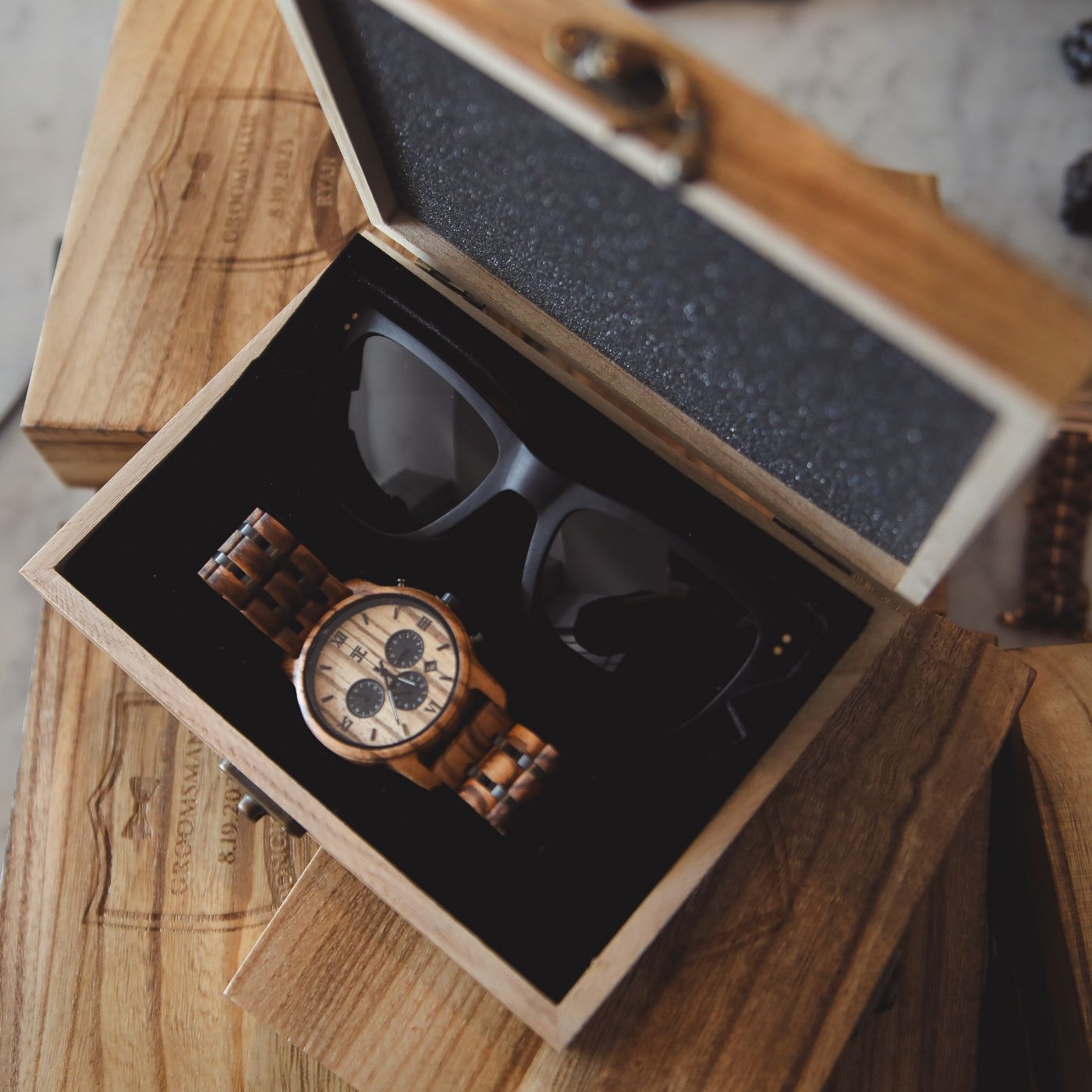A wooden watch and sunglasses displayed together inside a wooden box, showcasing a natural and stylish accessory combination.