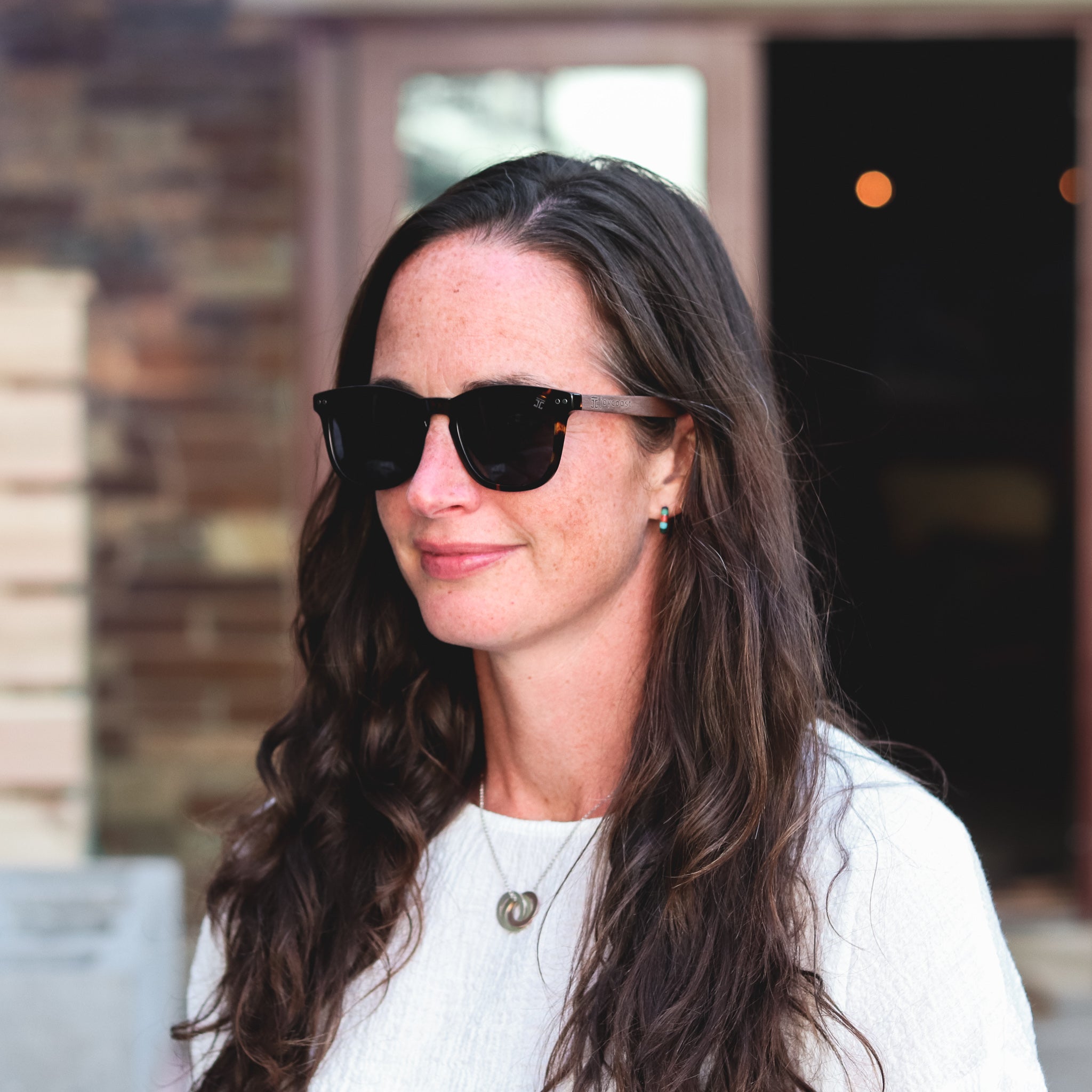 Joycoast "Stevi" sunglasses as shown on model. Dark tortoise sunglasses with a square frame and walnut wood arms.