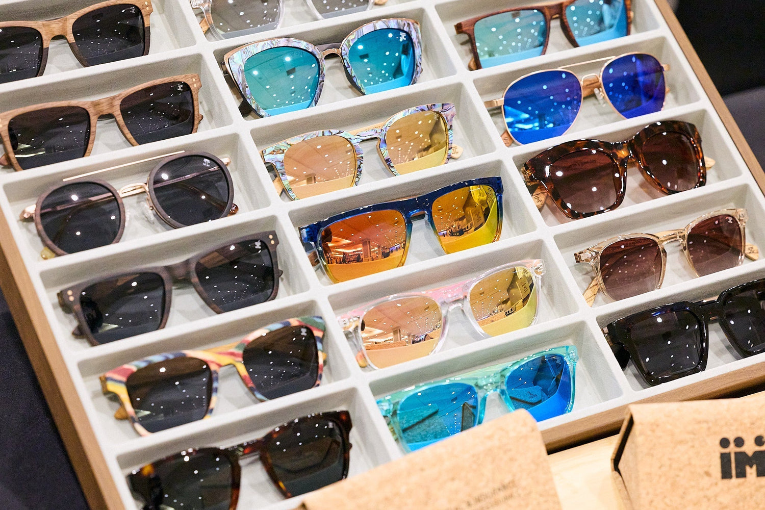 Display box with a variety of colorful wooden frame sunglasses with mirrored and tinted lenses by Joycoast