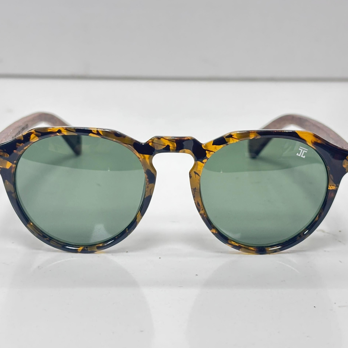 Round tortoiseshell wooden sunglasses, front view, with green lenses