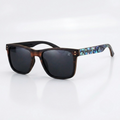 Side view of ebony wood sunglasses with dark lenses and iridescent abalone-pattern temple