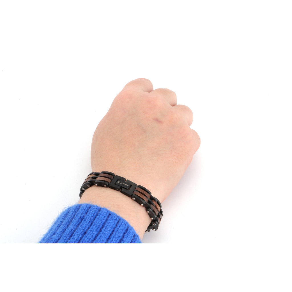 Men's wood bracelet on wrist; brown slat links with black strap and buckle
