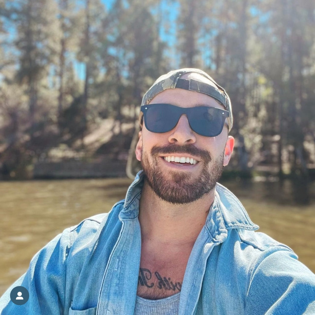 Dark navy sunglasses with mirrored lenses and light wood temple arms, frameless style