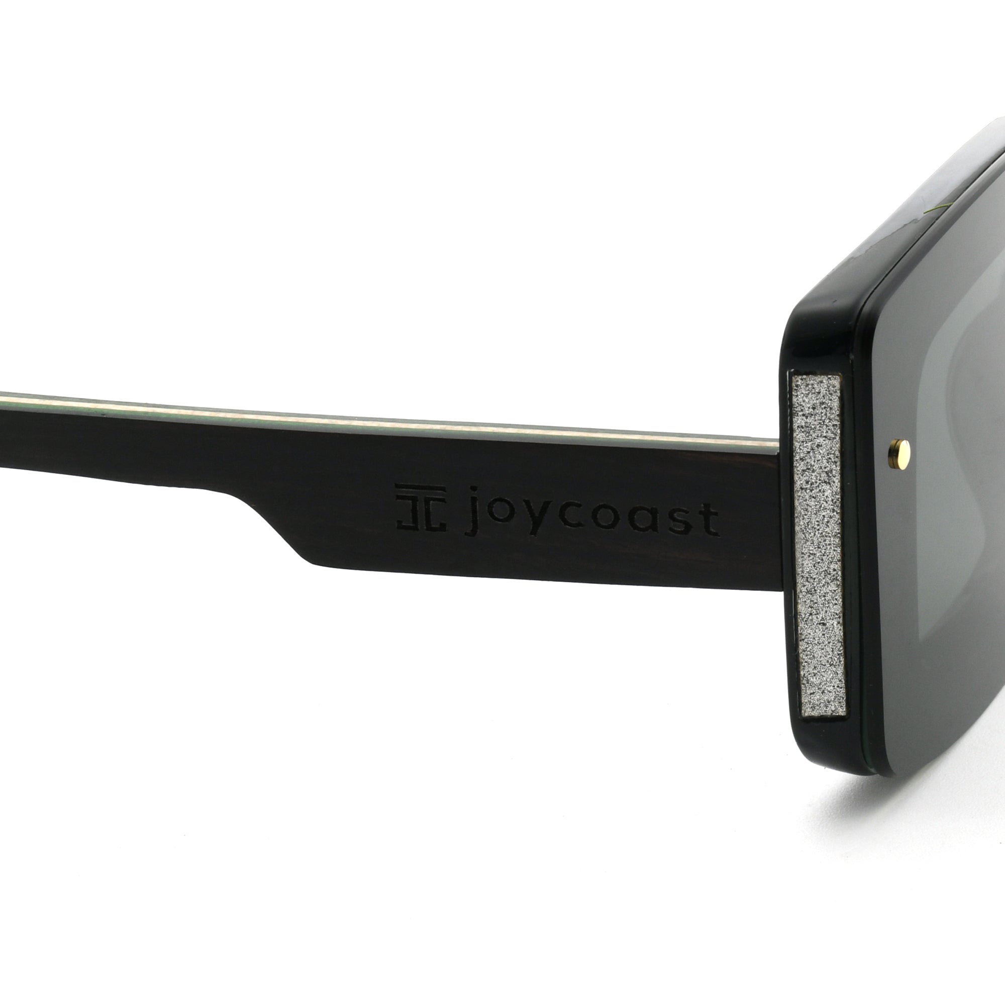 Close-up of a black wooden sunglasses arm with the "Joycoast" logo engraved.