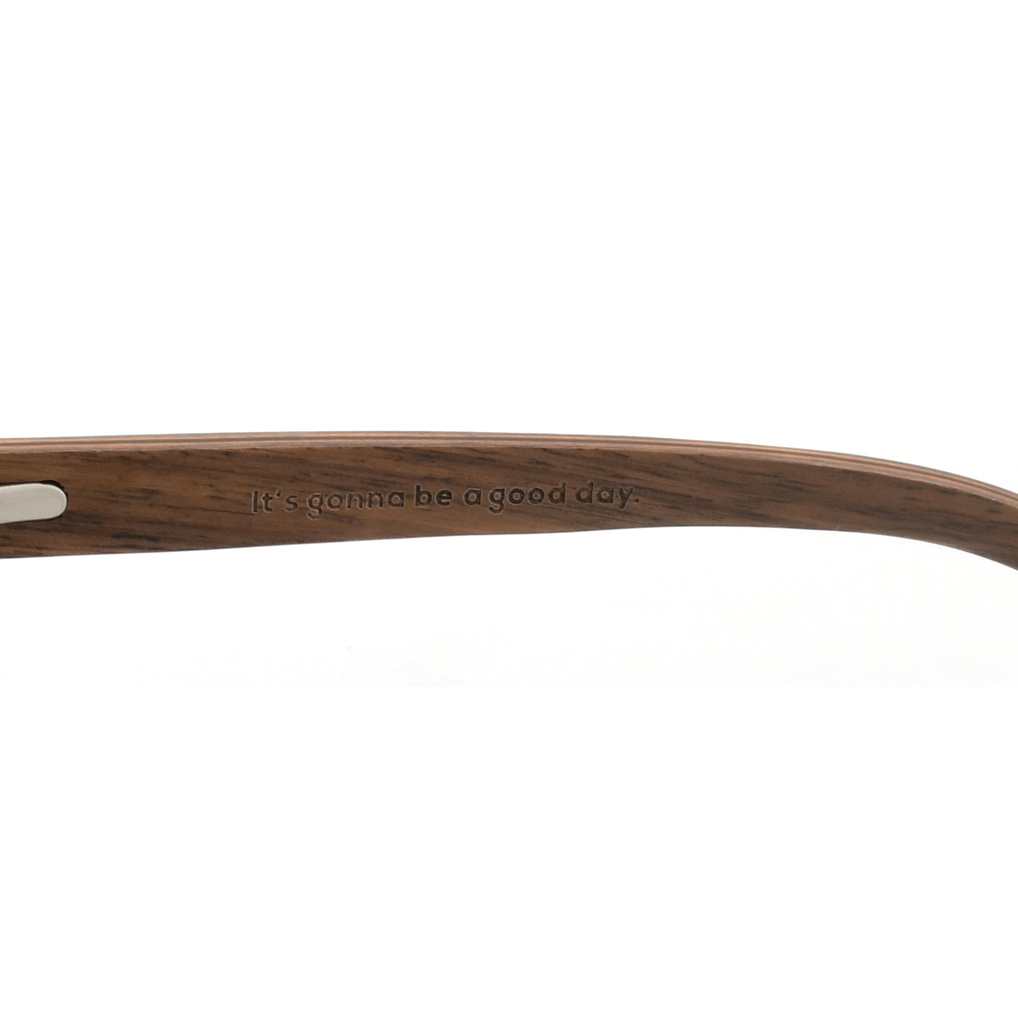 Close-up of a brown wooden sunglasses arm with the Joycoast slogan, "It's gonna be a good day." engraved.