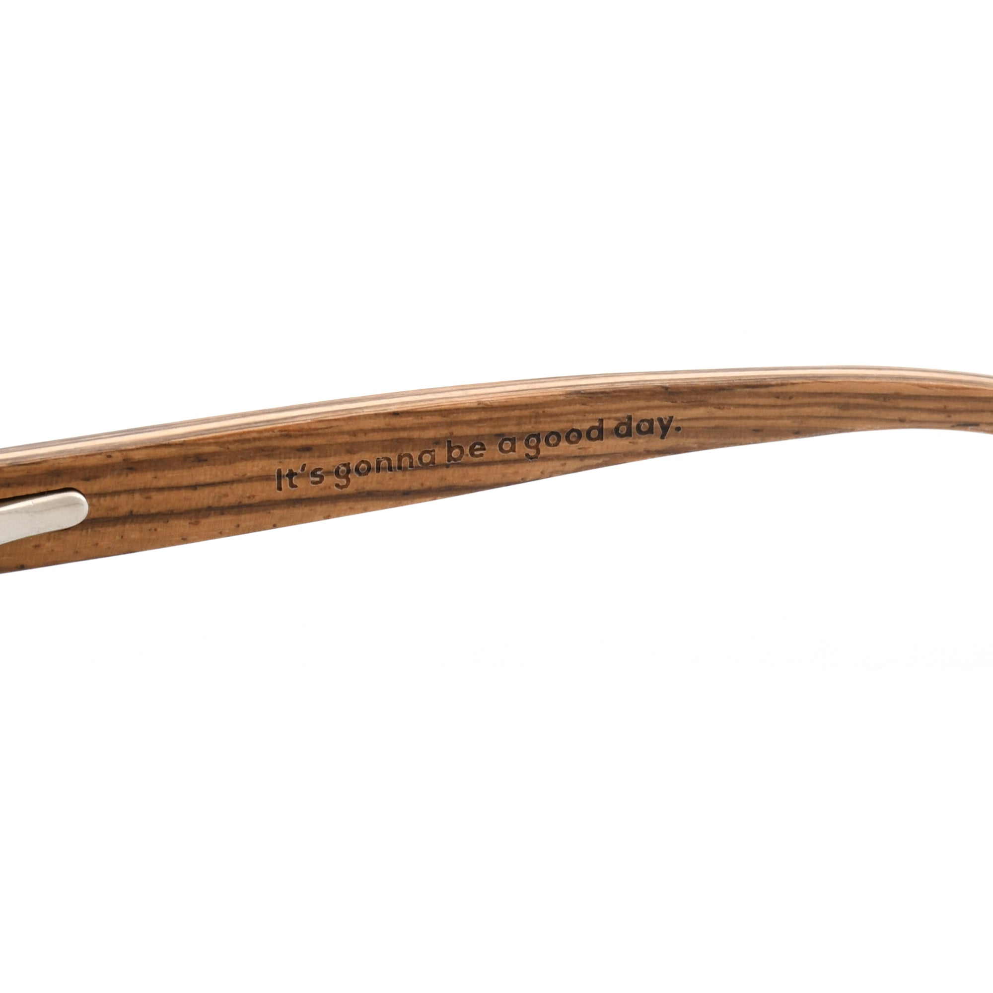 Close-up of a brown wooden sunglasses arm with the Joycoast slogan, "It's gonna be a good day." engraved.