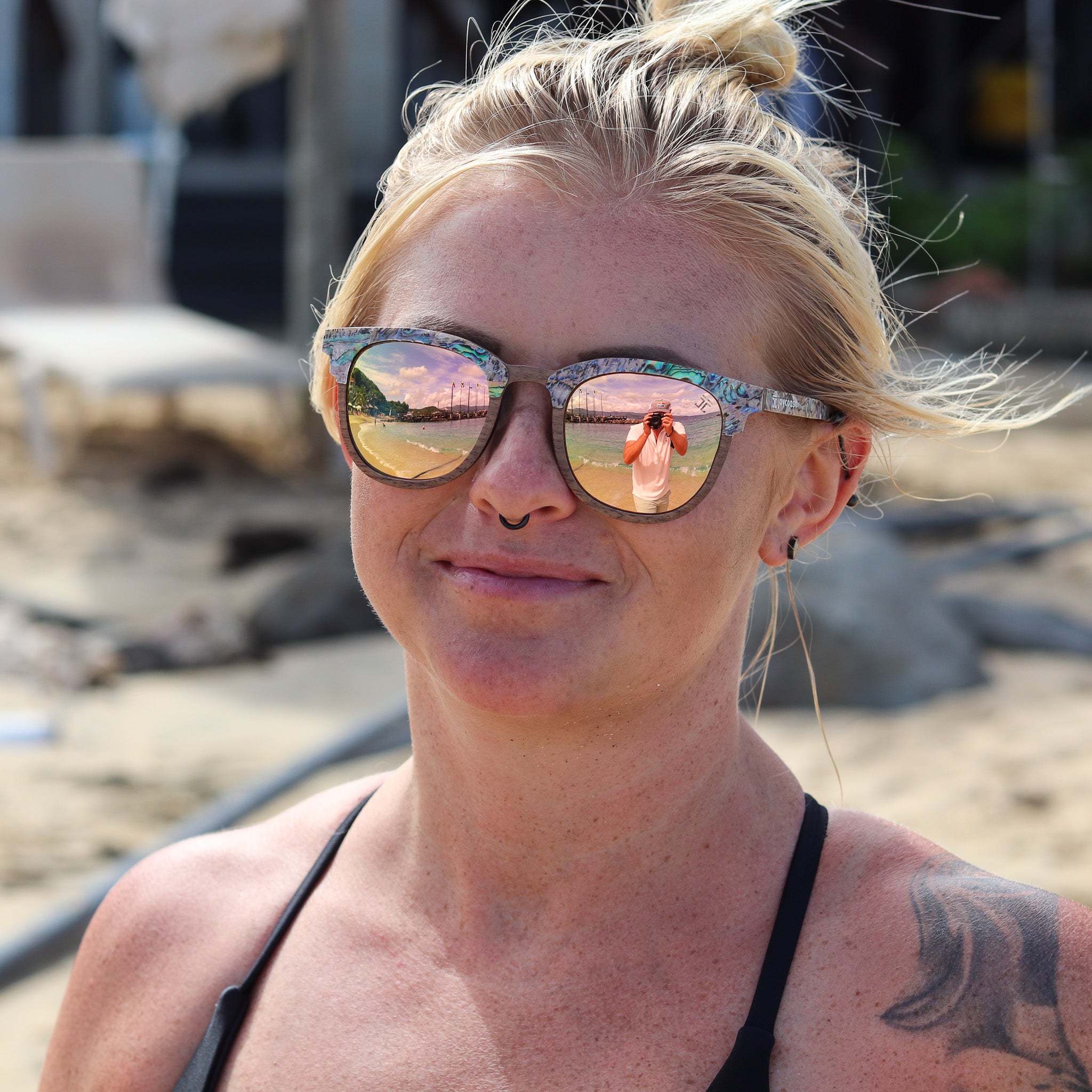 Round wooden sunglasses on a person with abalone-style frame and mirrored lenses