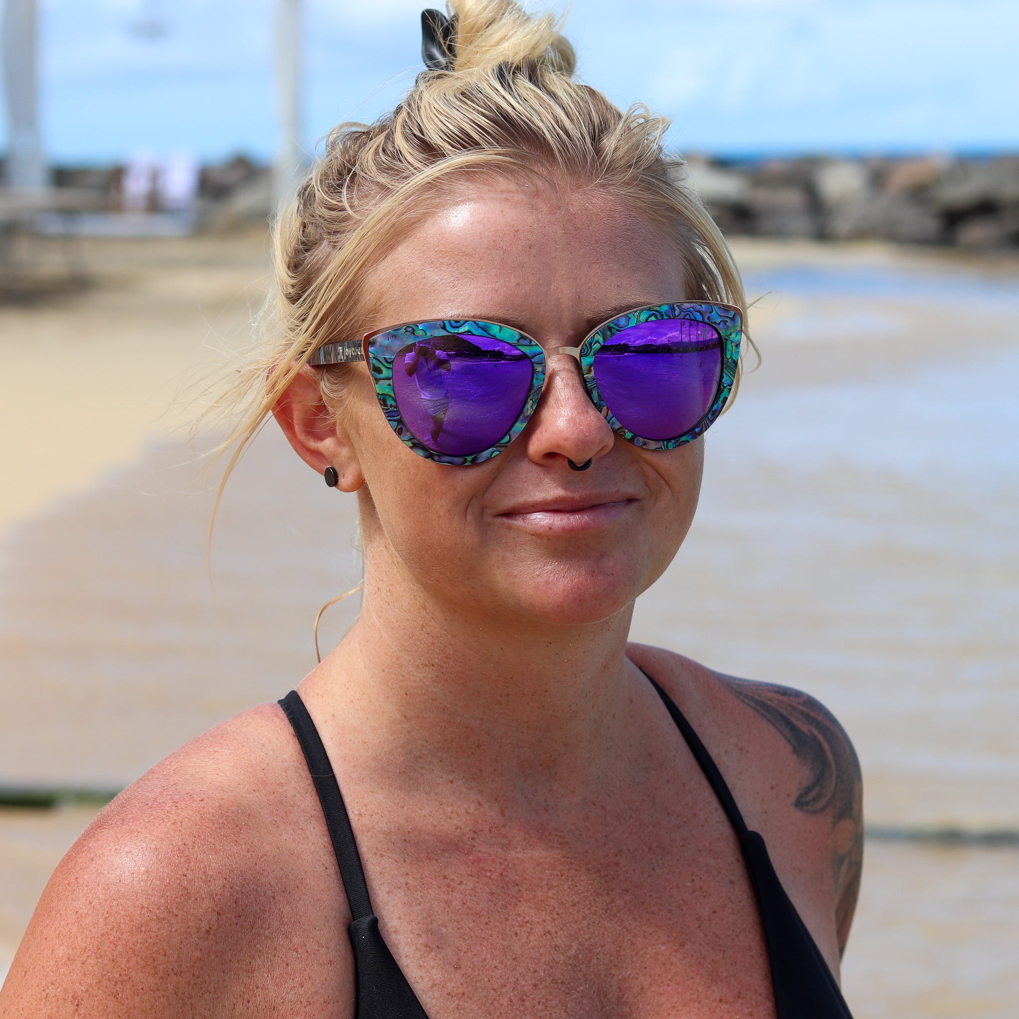 Cat-eye sunglasses worn with reflective purple lenses and marbled blue frame