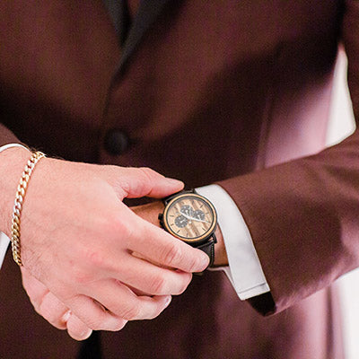 A man in a suit is adjusting his watch, showcasing a professional appearance and attention to detail.
