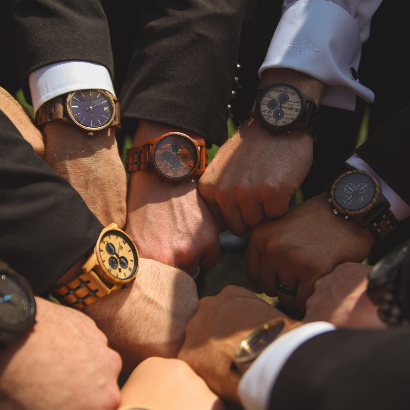 A group of men wearing various watches, gathered in a circle, showcasing their timepieces and engaging in conversation.
