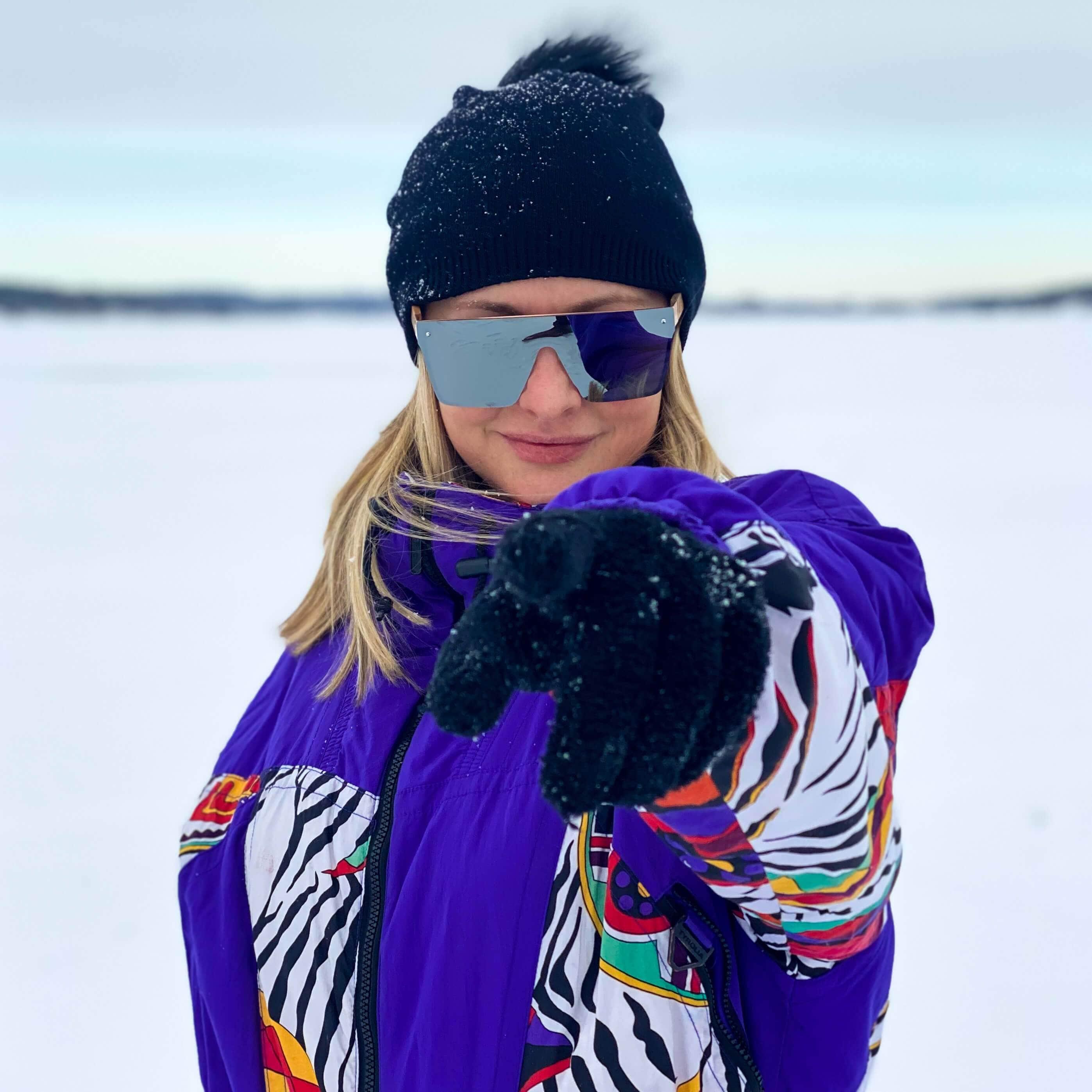 Apres-ski frameless sunglasses with blue lenses and dark frame, worn outdoors
