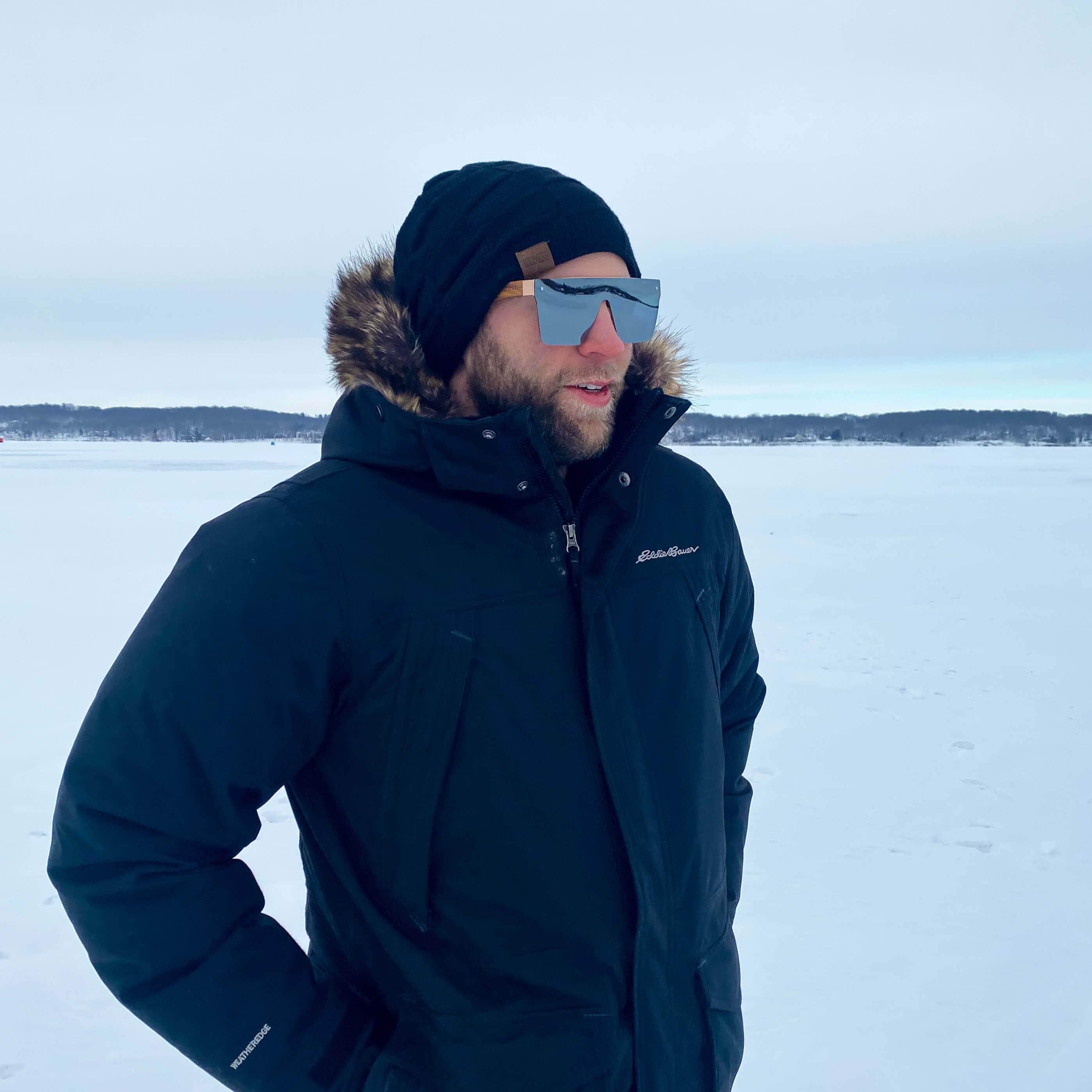Apres-ski frameless sunglasses with light blue lenses and dark frame, worn outdoors