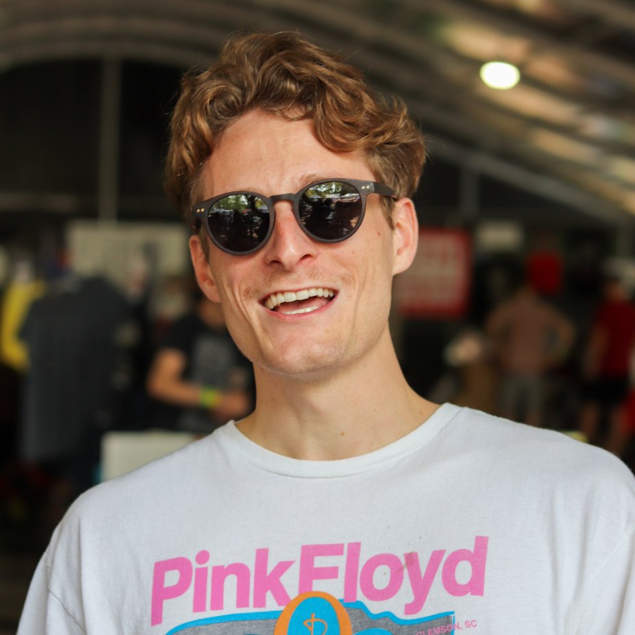 Person wearing round dark-lens sunglasses with dark brown frame