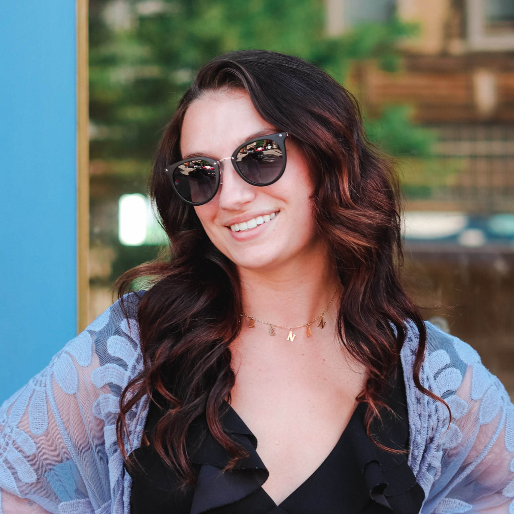 Black cat-eye sunglasses with grey tinted lenses on a person